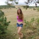 Smiling blonde Anna B undresses in mountains