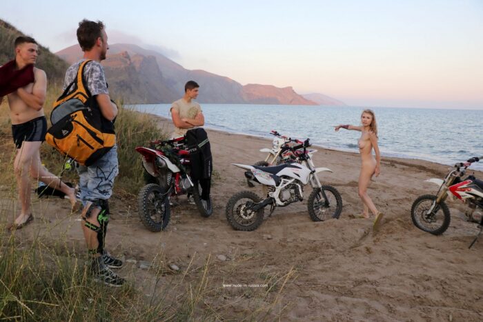 Naked russian babe Eva Gold rides a motorcycle with strangers at sandy beach