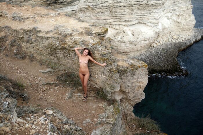 Naked girl Valentina K shows hairy pussy on a cliff by the sea