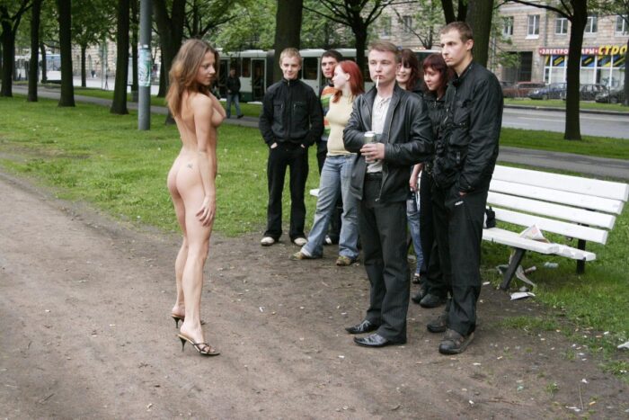 Fully naked girl Janina M in the company of dressed strangers in the park