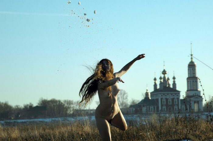 Long-haired girl Angelika without clothes posing on a snowy field