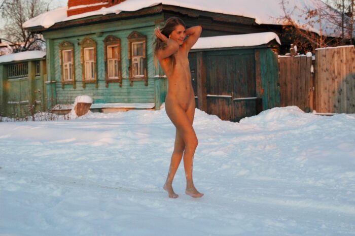 Slender blonde Sveta S with small tits walks through the snow in the village