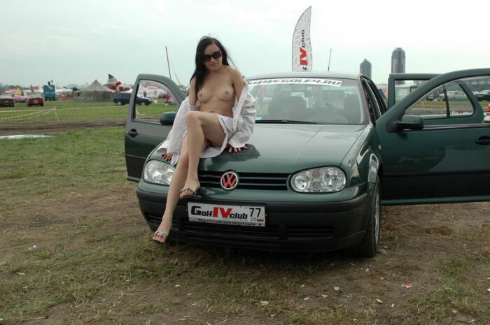 Smiling girl shows her body at the exhibition of cars