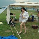 Smiling girl shows her body at the exhibition of cars