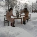 Two girls without clothes drink tea outdoors at winter