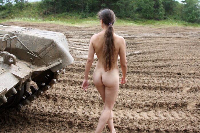 Margarita menina nua com peitinhos em um campo de tanques