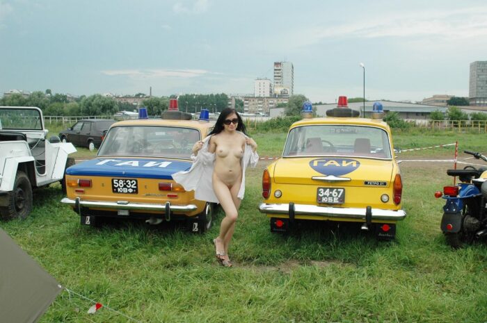 Russian teen brunette in sunglasses near old police cars
