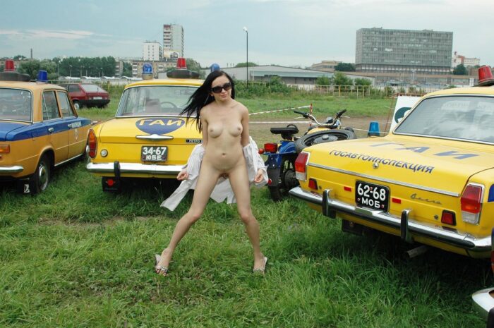 Russian teen brunette in sunglasses near old police cars