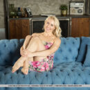 Gorgeous blonde Anna Delos flings her sexy toes up in the air and exposes her bottomless smooth cunt on the blue sofa.