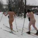 Two girls without clothes skiing in the snowfall