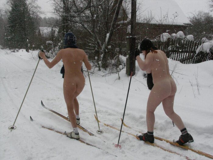 Two girls without clothes skiing in the snowfall