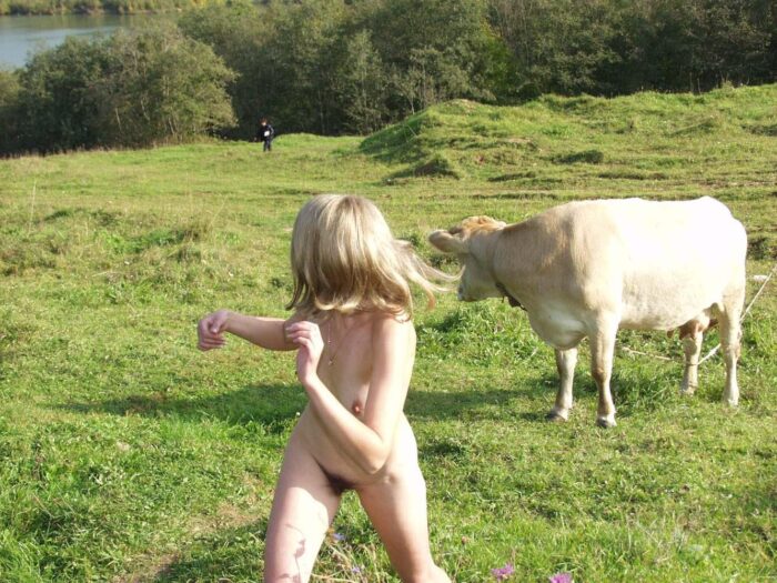 Blonde Natalia K is photographed naked with cow in nature