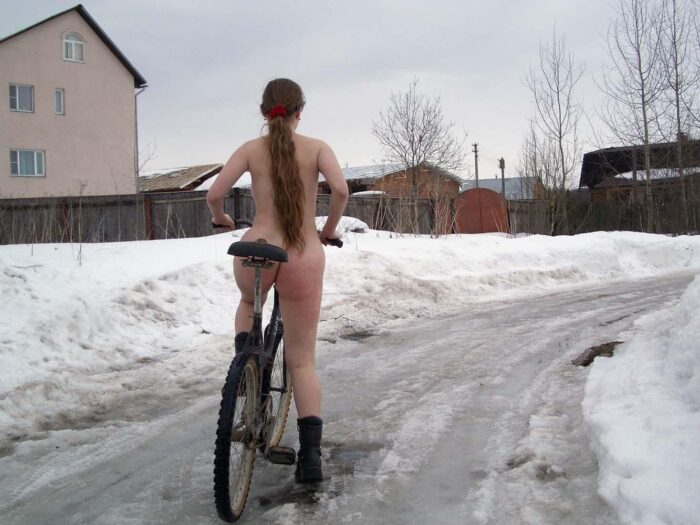 Teen blonde Alena B rides a bycicle at winter