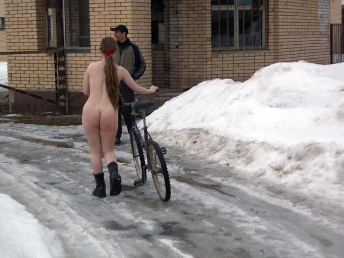 Teen blonde Alena B rides a bycicle at winter