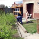 Two girls help a man saw a log naked