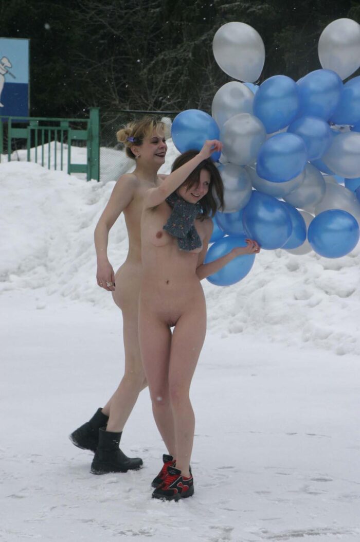 Two naked girls play with balloons at winter outdoors