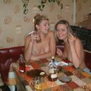 Two naked girls smoke and drink in the kitchen