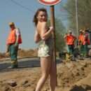 Girl Tanya takes off a dress in front of road workers