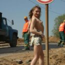 Girl Tanya takes off a dress in front of road workers