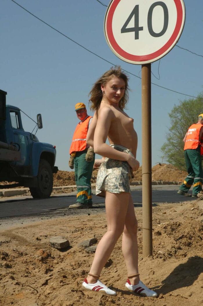 Girl Tanya takes off a dress in front of road workers