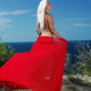 With a bright red scarf floating daintily along the wind, Adele exudes a breathtaking vision of radiant beauty and feminine gracefulness against the majestic blue sky.