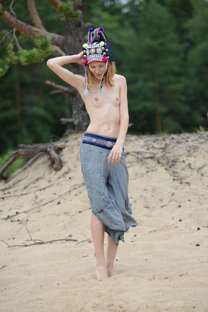 Shanty A in a tribal headdress ravishingly flashes her topless slim figure and hairless coochie outdoors on the sand. 
