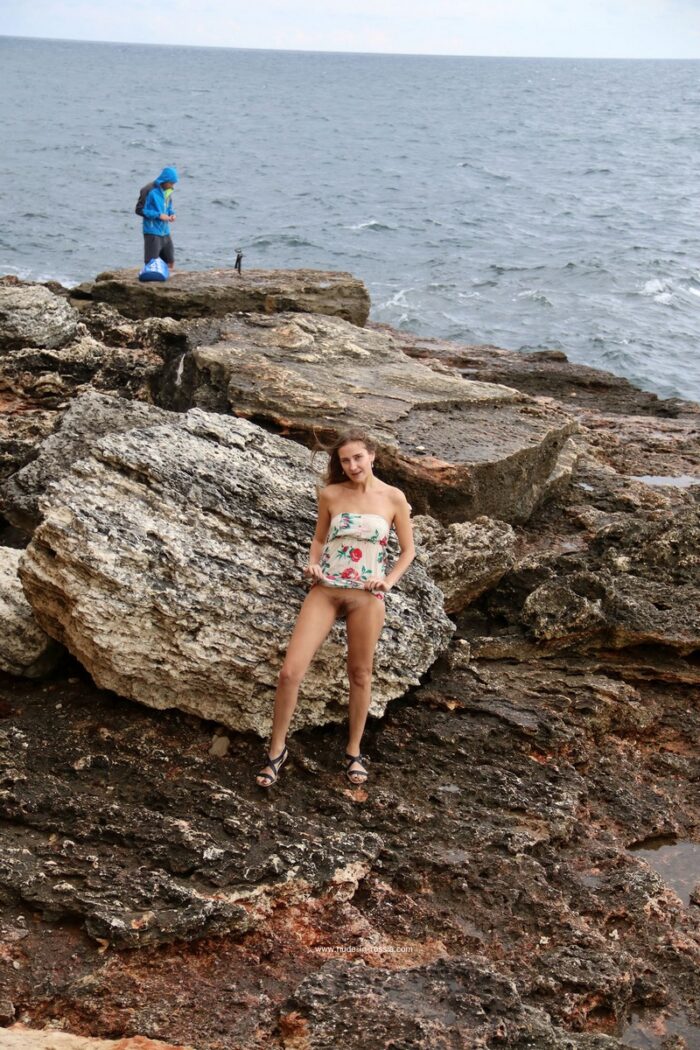 A slender girl Valentina K with an unshaven pussy walks along the rocky shore
