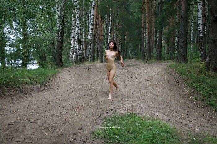 A young and beautiful brunette Dayana walks naked in the woods