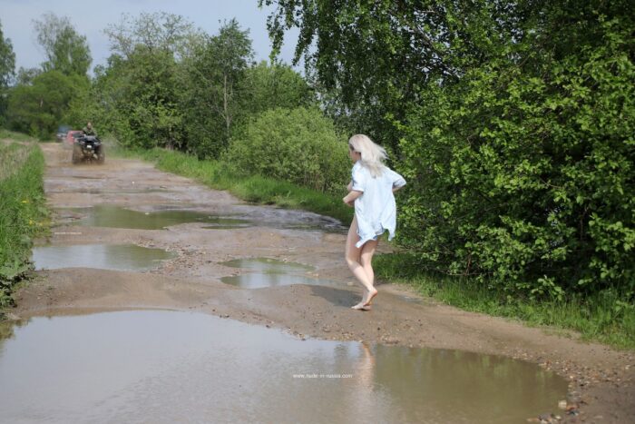 Blonde girl Lenochka taking pictures in a puddle