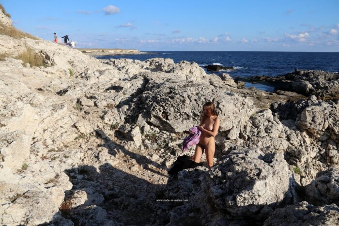 Blonde girl Valentina K undresses on sea rocks