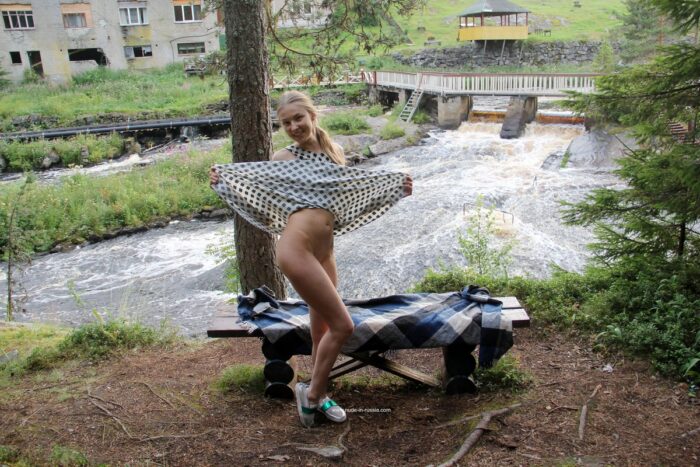 Cute young blonde Nimfa takes off her dress on a bench in the woods