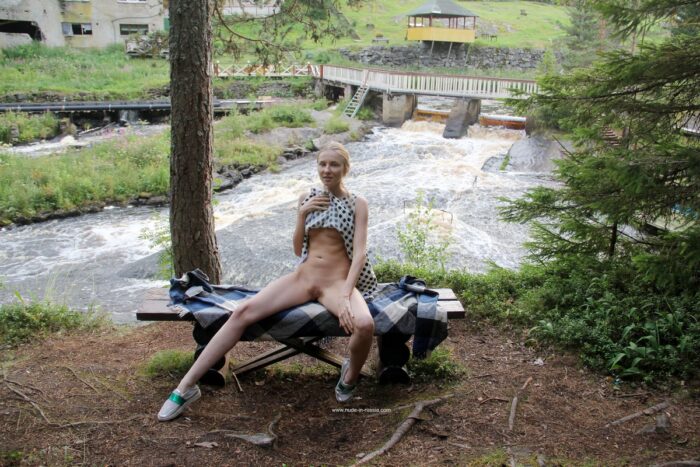 Cute young blonde Nimfa takes off her dress on a bench in the woods