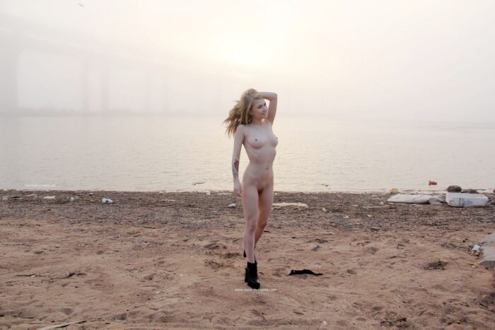 Hot blonde babe Eva Gold in boots on the morning city beach