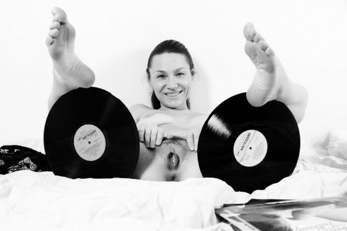 Smiling girl Irena K with beautiful ass and cunt posing with records