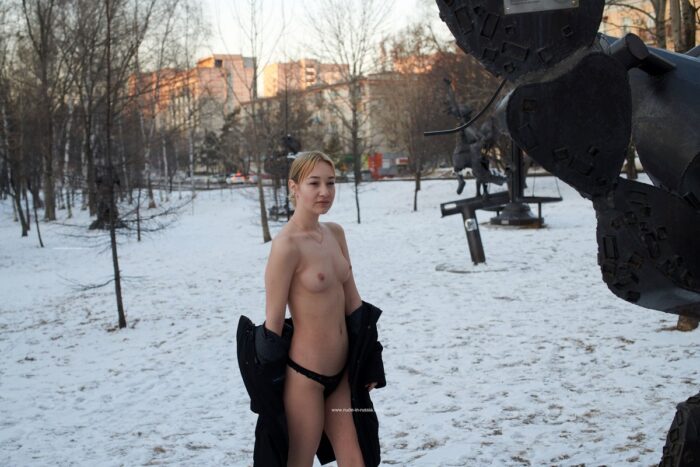 Young blonde Alexandra B posing in a fur hat in a city park