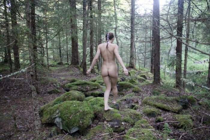 Naked girl Abbey walking with a camera through the forest