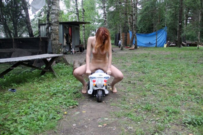 Redheaded girl Lera S plays with a toy motorcycle