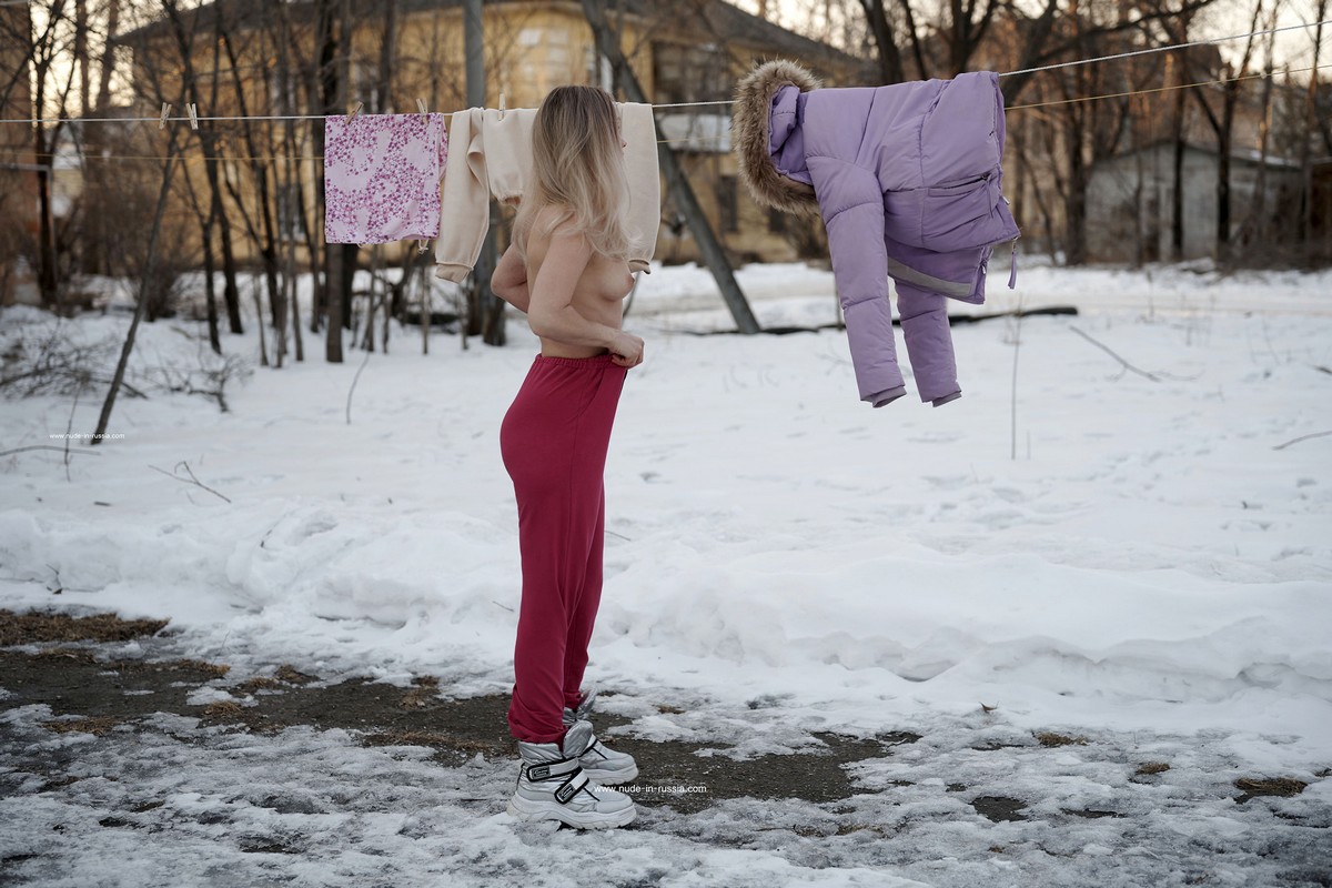 A beautiful girl Ornella decided to dry her things in the public yard at winter