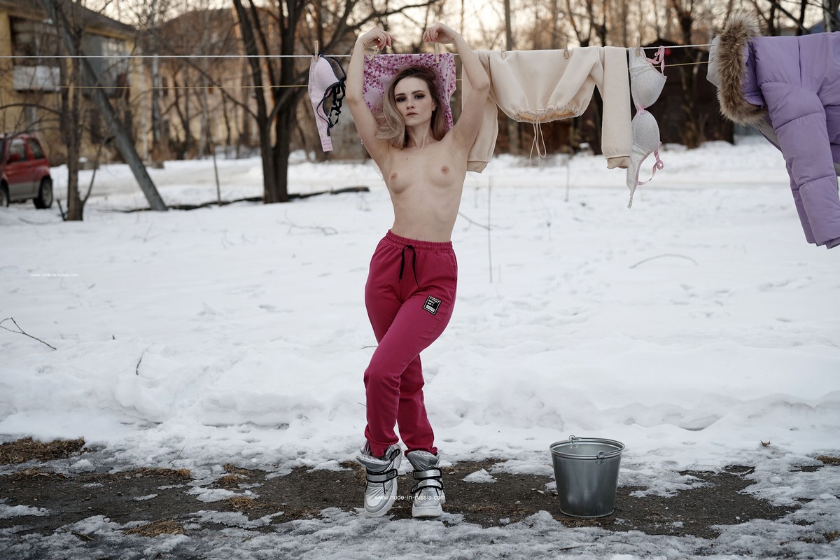 A beautiful girl Ornella decided to dry her things in the public yard at winter