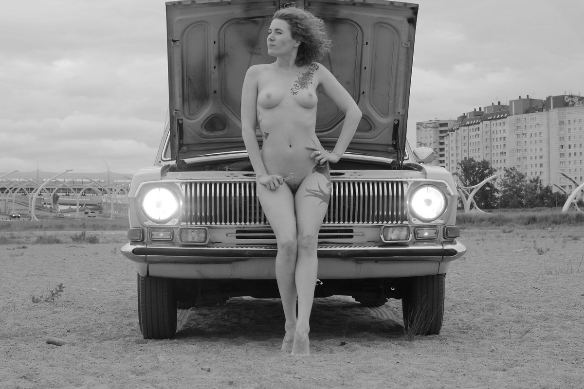 Curly red-haired girl Tatyana posing with an old taxi car