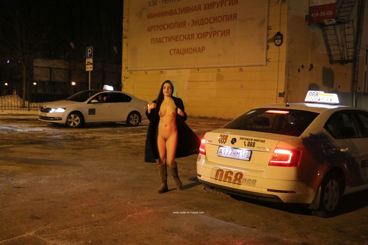 Long-haired brunette Natasha smokes on a winter street in the city