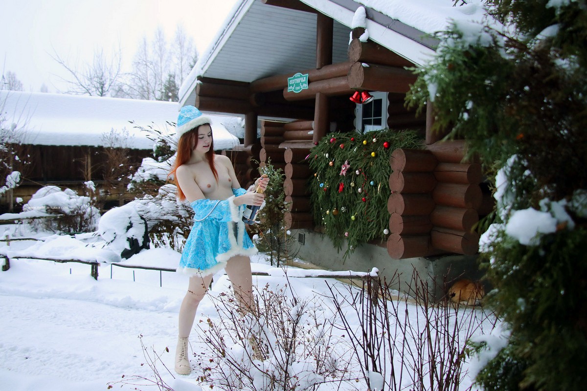 Red-haired Snow Maiden drinks champagne near a country house