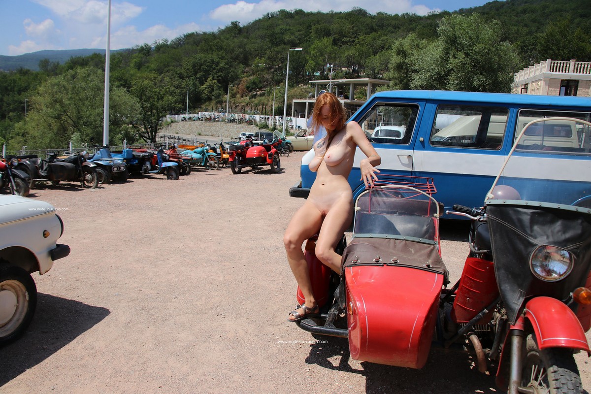 Redheaded girl Xenia posing in outdoors museum of old cars
