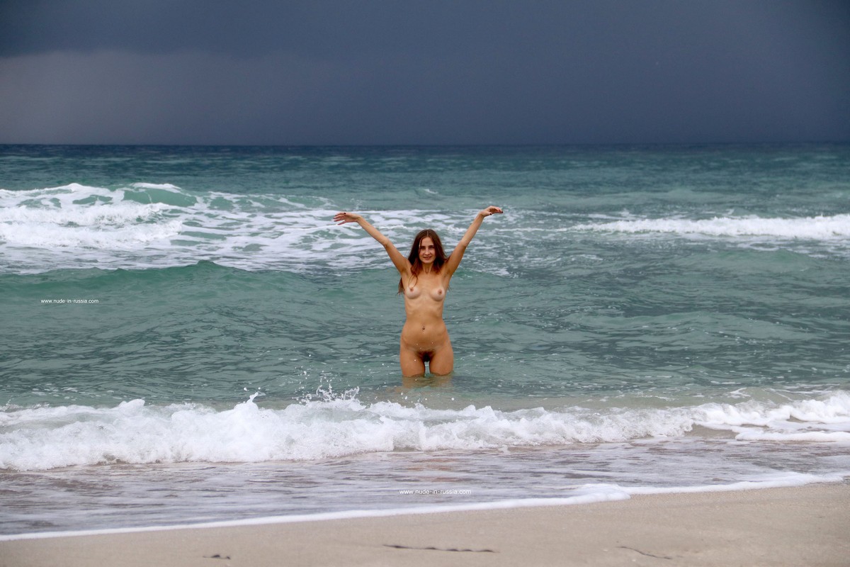 Smiling young girl Valentina K bathes in the sea before a thunderstorm
