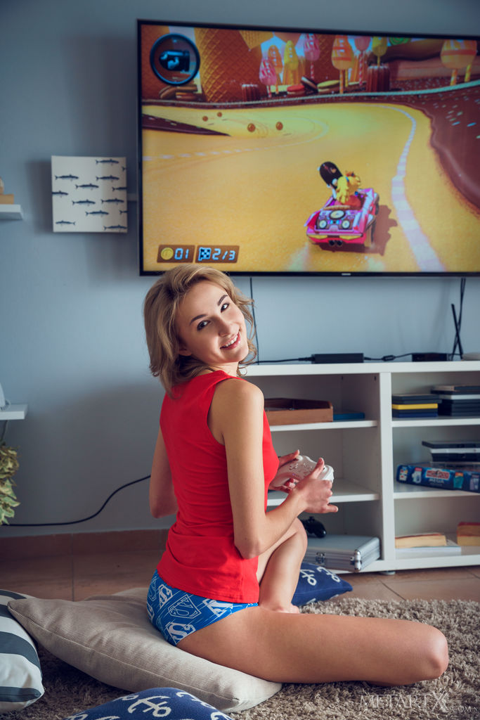 Lovely Lea Rose is playing with the game console and decides to take off her red shirt and uncover her erect nipples then bends over,sticking her finger into her hairless pussy.