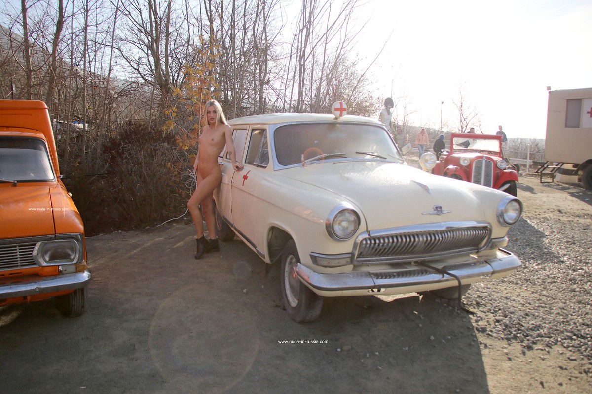 Slender blonde Bella without clothes posing with old soviet cars