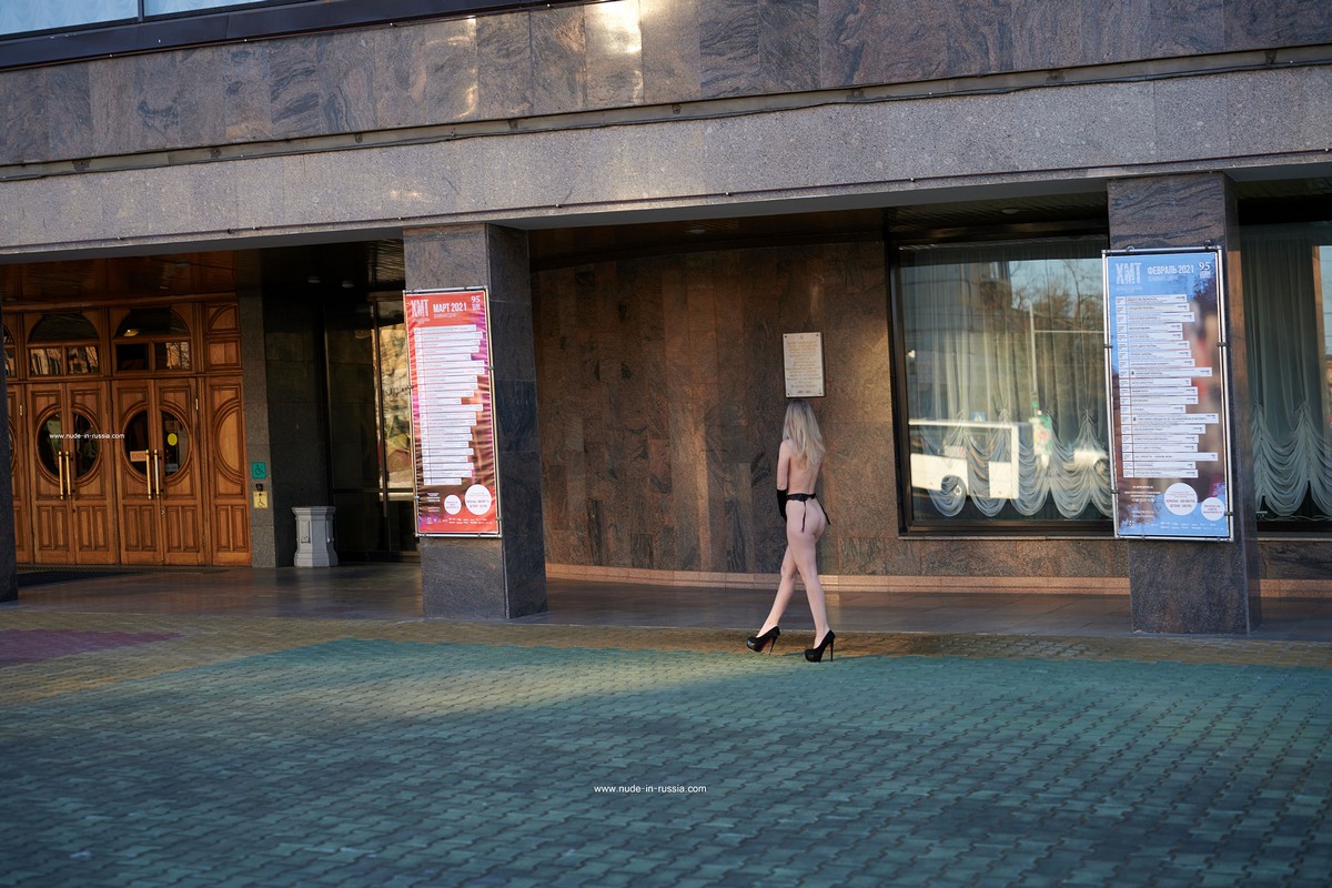 A blonde Ornella with a gorgeous body in a sexy outfit walks in front of the theater square