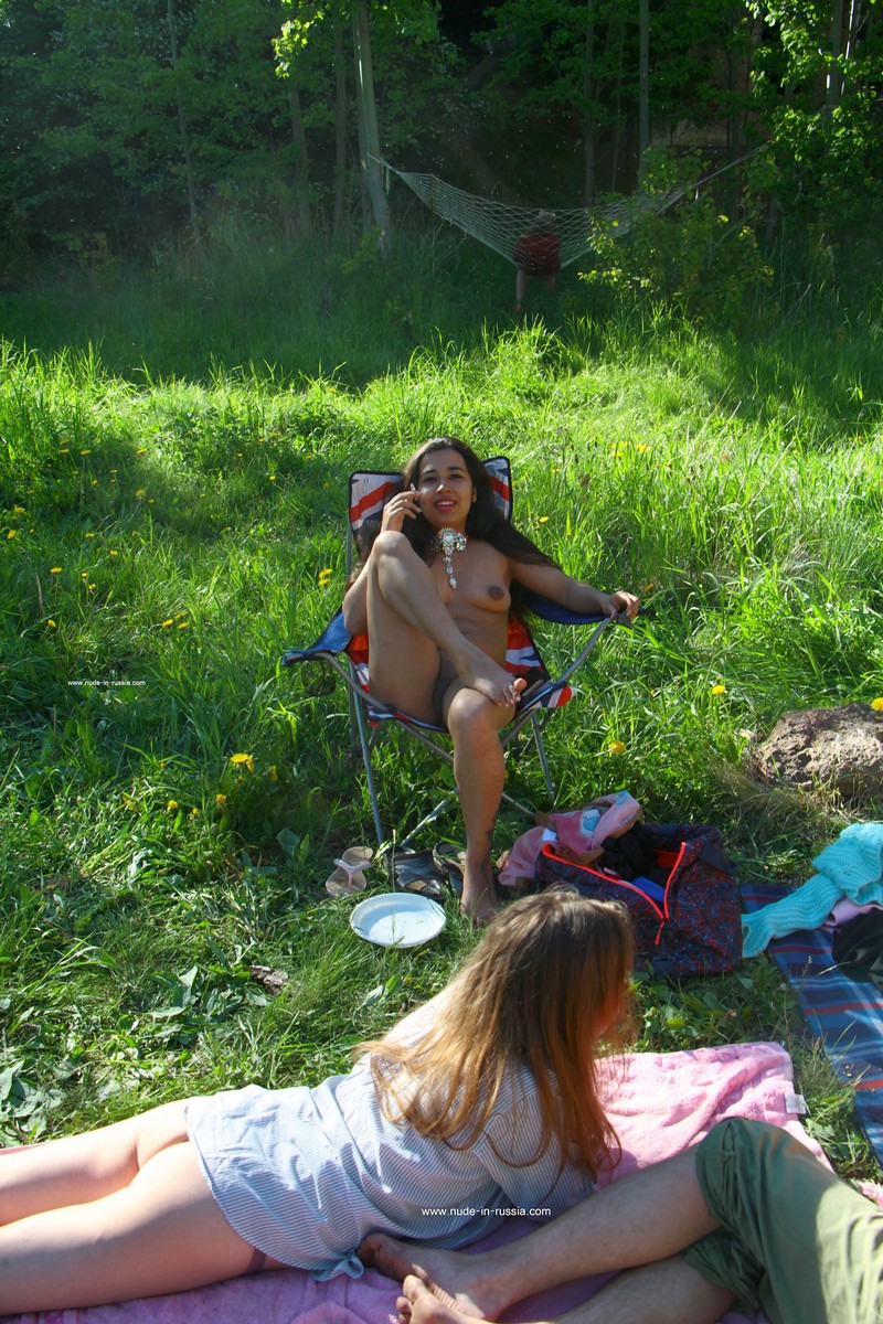 Long-haired Asian brunette smokes with her legs spread outdoors