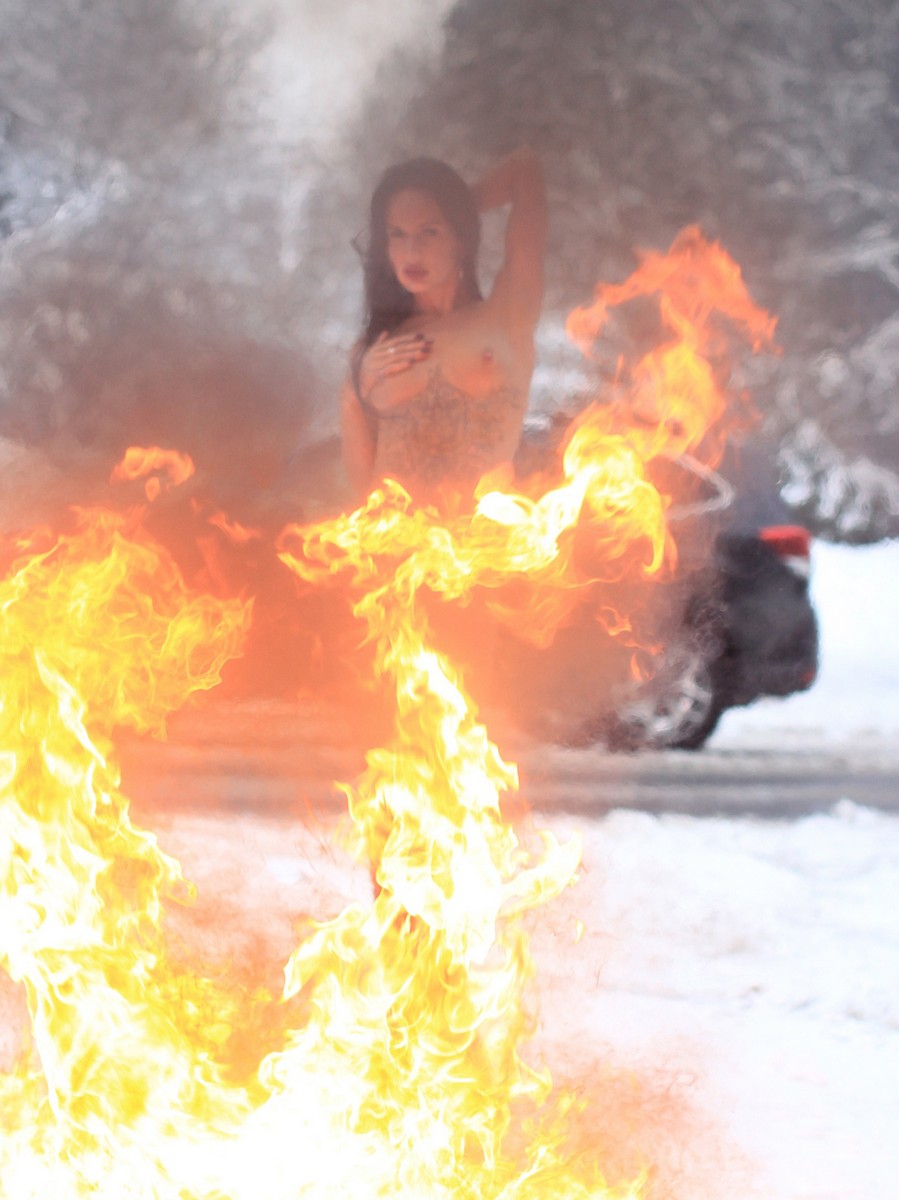 Long-haired brunette Katerina burns her clothes near a winter road
