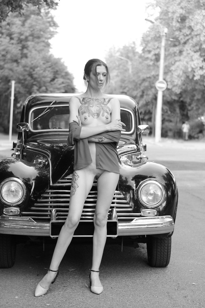 Tattooed and pierced skinny girl Lia A in an old car